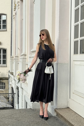 a lady in a long black vest dress with a belt